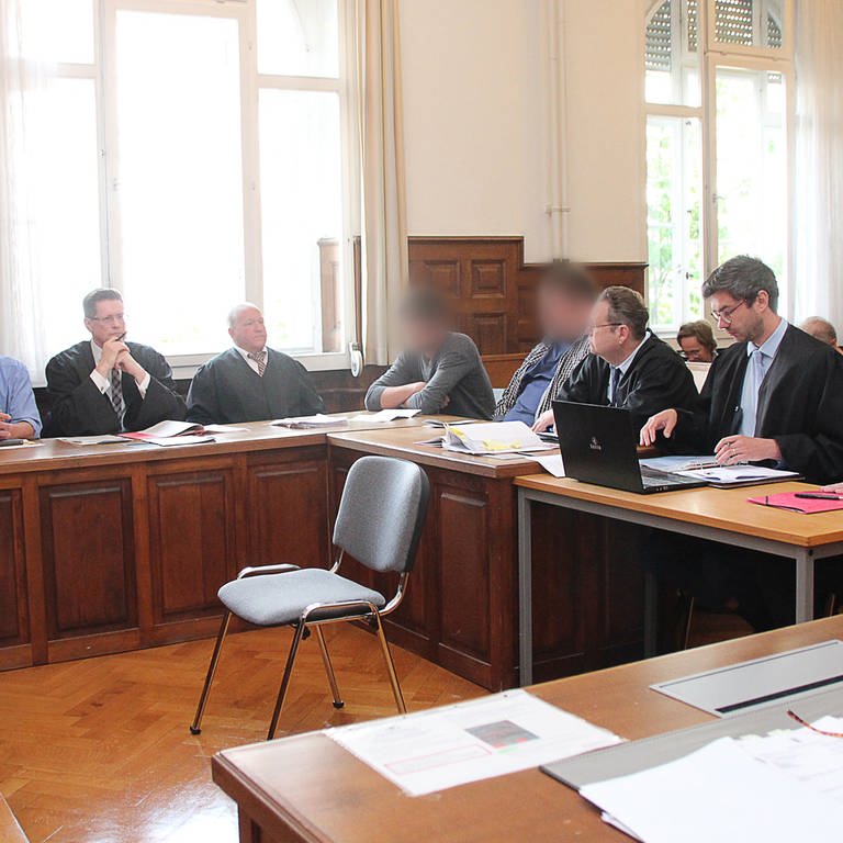 Vier Angeklagte sitzen mit ihren Anwälten im Amtsgericht Weinheim.