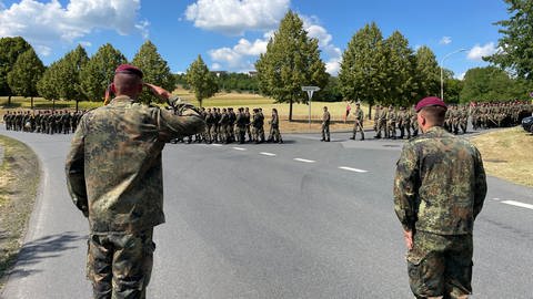 Ein Soldat salutiert als seine Kameradinnen und Kameraden des Panzerbatallion 363 Hardheim bei ihrer Verabschiedung zum NATO-Einsatz nach Litauen maschieren. 
