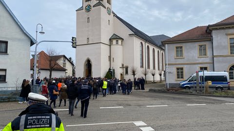 Schülerinnen, Schüler, Lehrerinnen und Lehrer sowie Polizei- und Rettungskräfte vor der Kirche