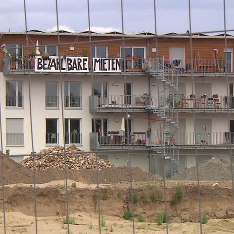 Ein Haus mit einem Banner mit der Aufschrift: "Bezahlbare Mieten". Die Sozialquote für Wohnungsmieten ist Thema im Mannheimer Gemeinderat