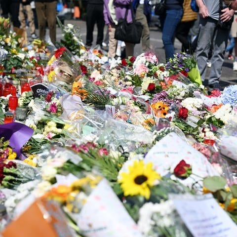 Nach dem Tod eines Polizisten, der nach einer Messerattacke mit mehreren Verletzten gestorben ist, liegen am Marktplatz in der unmittelbaren Nähe des Tatorts Blumen und Kerzen. 