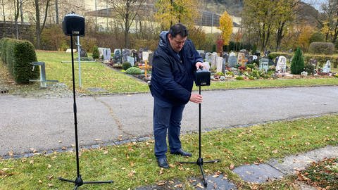 Pfarrer Ralf Baumgartner baut die Lautsprecheranlage auf dem Friedhof auf. Mit dem Brummen und Surren der Autos von der Autobahn kann man ihn sonst bei Beerdigungen kaum verstehen.   (Foto: SWR, Katja Trautwein )