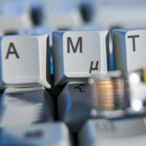 Der Schriftzug "Amt" ist auf einer Computertastatur hinter einem Netzwerkkabel zu sehen. (Foto: picture-alliance / Reportdienste, picture alliance/dpa/dpa-Zentralbild | Jens Büttner)