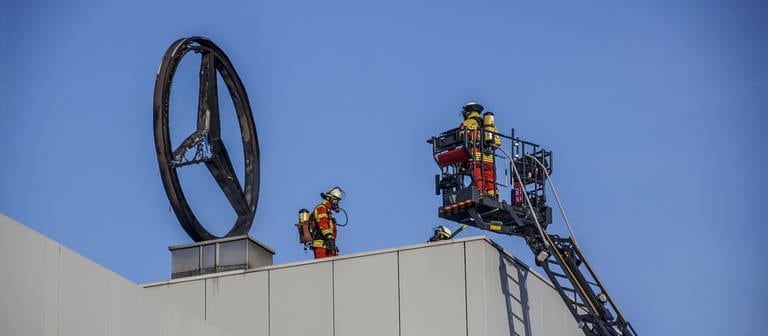 Feuerwehrleute stehen neben einem verbrannten Mercedes-Stern auf dem Dach eines Firmengebäudes. (zu "Mercedes-Stern geht in Flammen auf") (Foto: dpa Bildfunk, picture alliancedpaSDMG  Dettenmeyer)