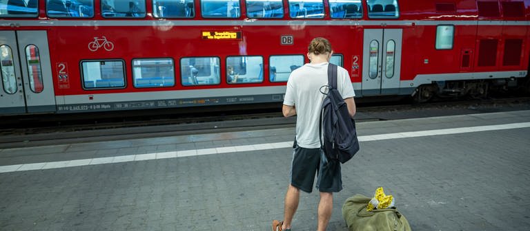 Ein junger Mann steht an einem Bahnsteig (Foto: picture-alliance / Reportdienste, picture alliancedpa  Peter Kneffel)