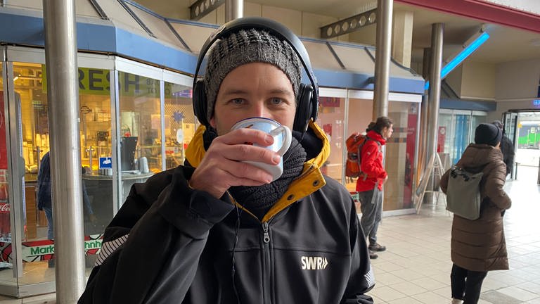 Ganz schön kalt, so lange am Bahnhof: SWR-Moderator Volker Wüst wärmt sich zwischendurch mal mit einer Tasse Tee auf. (Foto: SWR)