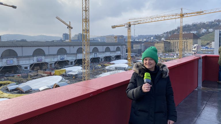SWR-Reporterin Ines Hennings auf dem Infoturm am Bahnhof mit Blick auf die S21-Baustelle. Laut Bahn soll der neue Tiefbahnhof Ende 2025 in Betrieb gehen. (Foto: SWR)