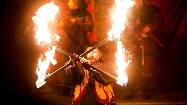 Ein mittelalterlich gekleideter Akrobat jongliert mit zwei brennenden Fackeln (Foto: Pressestelle, Esslingen Marketing)