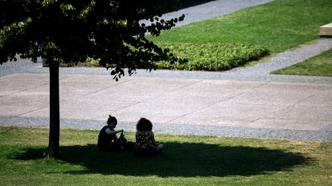 Zwei Frauen suchen unter einem Baum Schutz vor der Hitze.  (Foto: dpa Bildfunk, 4)