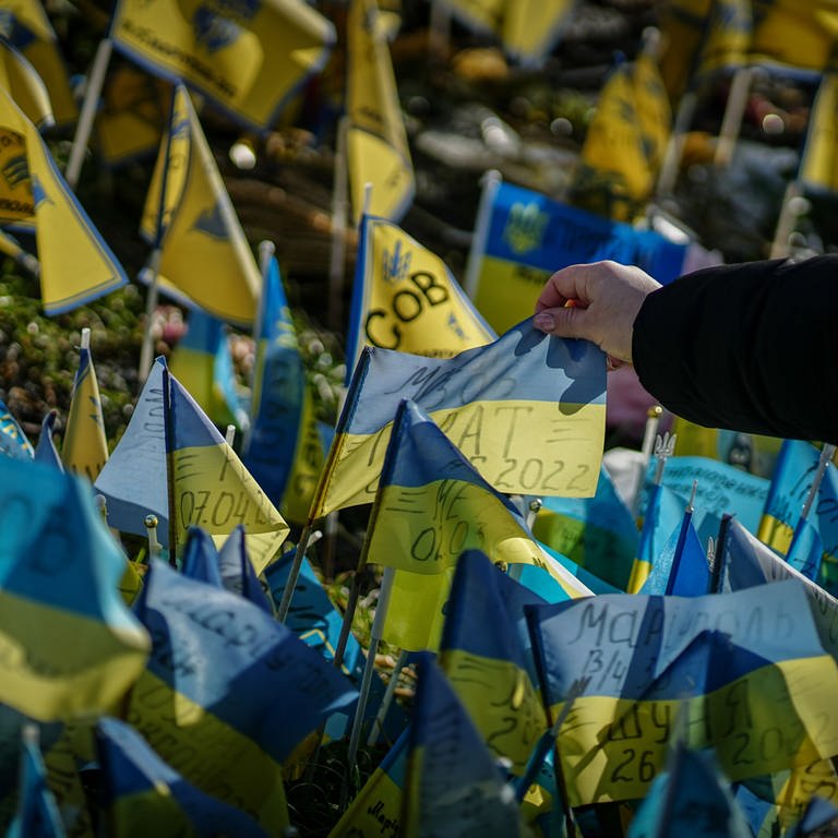 Am Jahrestag des Angriffs Russlands auf die Ukraine finden in der Region Stuttgart viele Veranstaltungen statt. Auf dem Bild schaut sich eine Passantin die Beschriftung auf einer ukrainischen Flagge für die getöteten Soldaten am Maidan an. (Foto: dpa Bildfunk, picture alliance/dpa | Kay Nietfeld)
