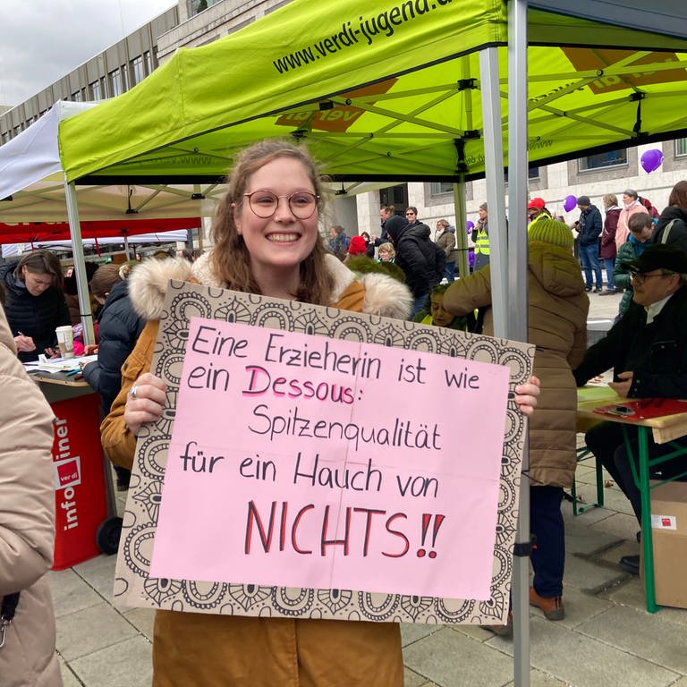 Eine Frau fordert höhere Löhne für Erzieherin. Auf ihrem Plakat steht: Eine Erzieherin ist wie ein Dessous: Spitzenqualität für ein Hauch von nichts! (Foto: SWR, Magdalena Haupt)