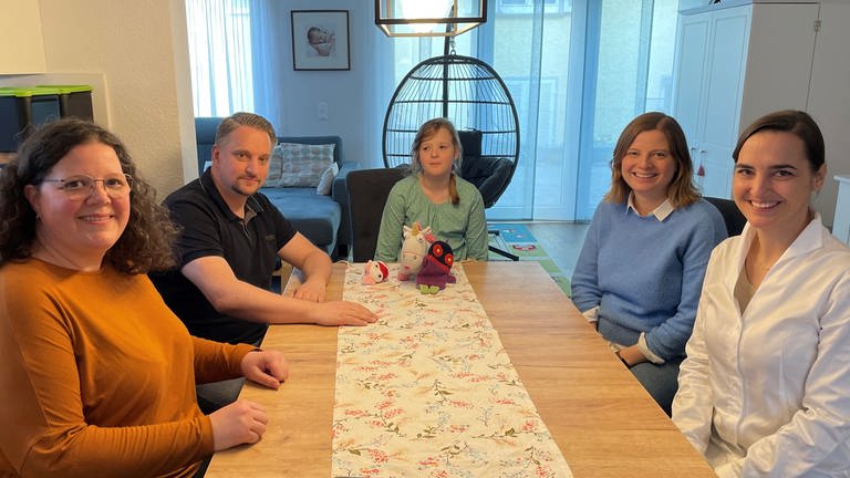 Bei Lea zu Hause: Die Neunjährige sitzt mit ihren Eltern sowie Psychologinnen und Ärztinnen zu Hause am Tisch. (Foto: SWR)