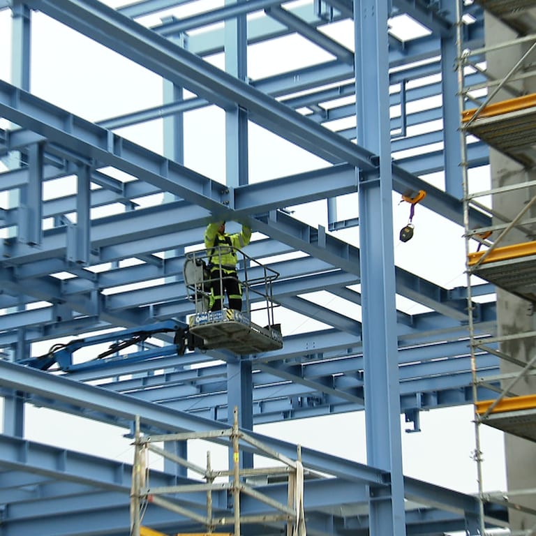Ein Mann montiert etwas in luftiger Höhe in einem Neubau eines Gas-Werkes der EnBW. (Foto: SWR)