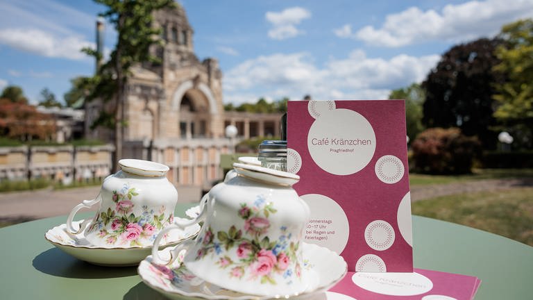 "Café Kränzchen" auf dem Pragfriedhof Stuttgart. Menschen sitzen an Gartentischen bei Kaffee und Kuchen. (Foto: Bürgerstiftung Stuttgart/Jan Potente)