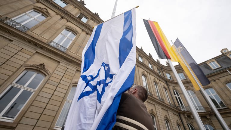 Ein Mitarbeiter des Staatsministeriums hisst eine Israel-Flagge. (Foto: dpa Bildfunk, picture alliance/dpa | Marijan Murat)