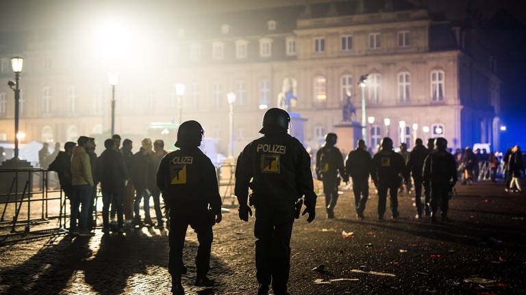 Polizeibeamte gehen in der Silvesternacht über den Stuttgarter Schlossplatz.