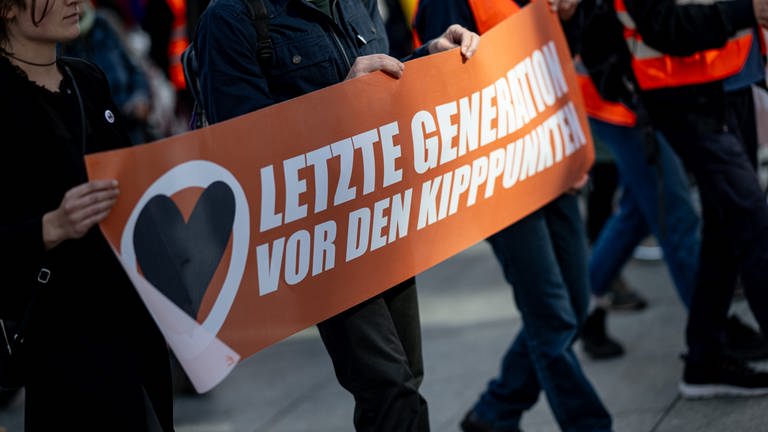 Banner mit der Aufschnitt "Letzte Generation vor den Kipppunkten" (Foto: dpa Bildfunk, Picture Alliance)