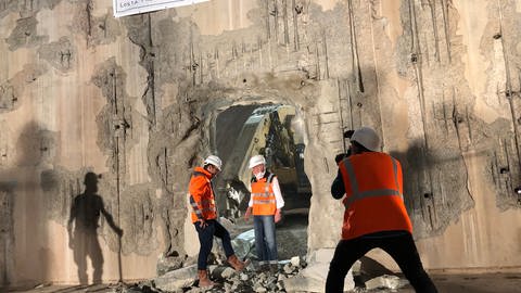 Mehrere Bauarbeiter in einem Tunnel, in den ein Bagger ein Loch geschlagen hat, (Foto: SWR, Philipp Pfäfflin)