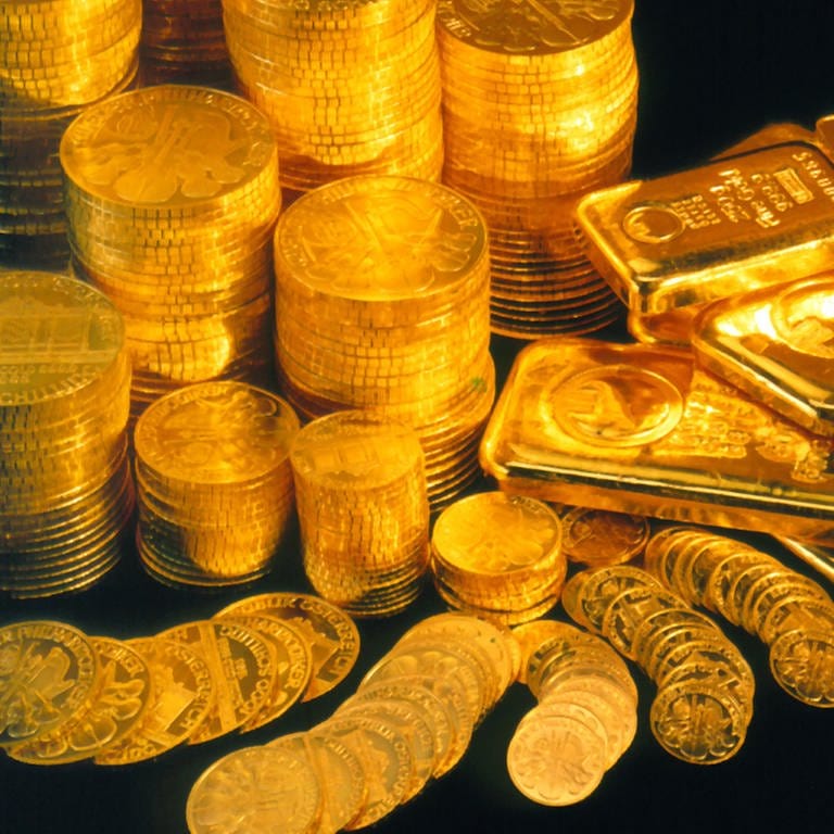 Glänzende Goldbarren und Goldmünzen auf schwarzem Untergrund