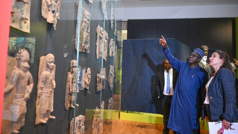 Abba Tijani (l), Generaldirektor der Nationalen Museums- und Denkmalbehörde Nigerias, und Ines de Castro, Direktorin des Linden-Museums, betrachten im Lindenmuseum Benin-Bronzen.