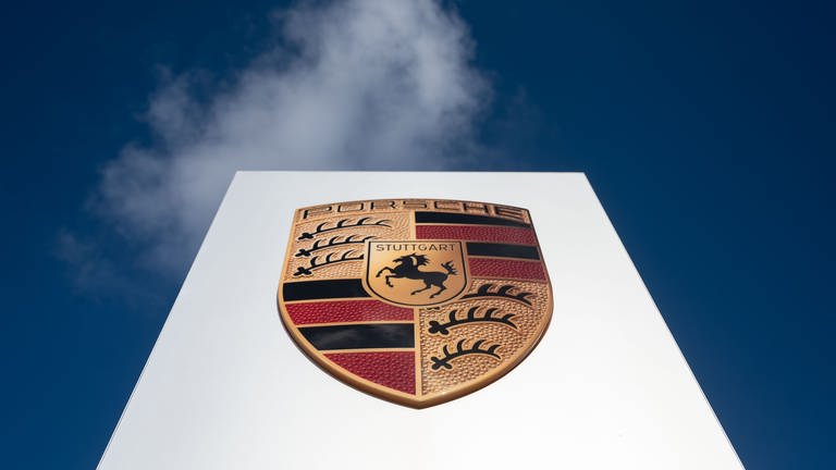 Das Logo der Porsche AG ist vor leicht bewölktem Himmel zu sehen.