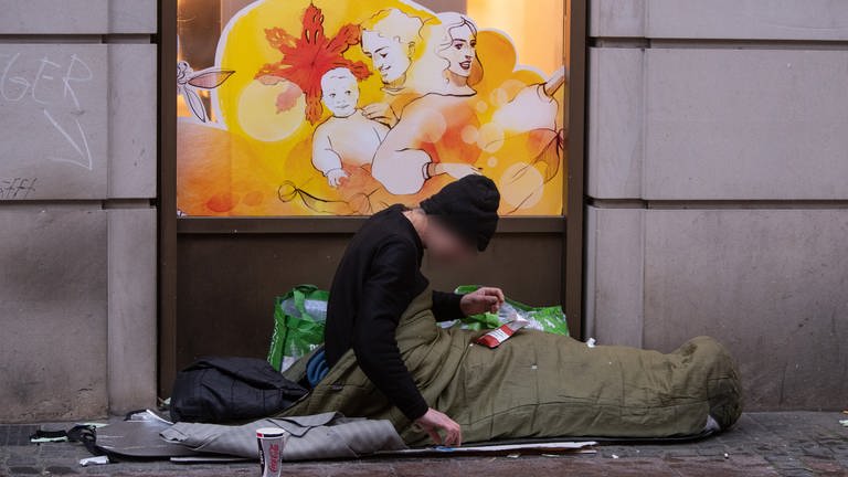 Ein obdachloser Mann liegt in seinem Schlafsack vor einer Drogerie in der Kaiserstraße im Bahnhofsviertel von Frankfurt. (Foto: dpa Bildfunk, Picture Alliance)