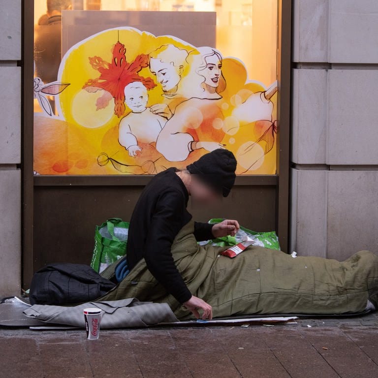 Ein obdachloser Mann liegt in seinem Schlafsack vor einer Drogerie in der Kaiserstraße im Bahnhofsviertel von Frankfurt. (Foto: dpa Bildfunk, Picture Alliance)