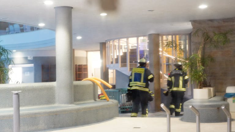 Feuerwehrleute gehen durch die Schwimmhalle eines Hallenbades. Wegen eines Gasalarms ist das Hallenbad Bietigheim-Bissingen geräumt worden. (Foto: dpa Bildfunk, picture alliance/dpa/Fotoagentur Stuttgart | Andreas Rosar)