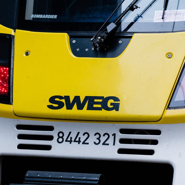 Menschen gehen an einem Zug mit dem Logo der SWEG vorbei. Die SWEG wird von der GDL bestreikt. (Foto: dpa Bildfunk, picture alliance/dpa | Ilkay Karakurt)