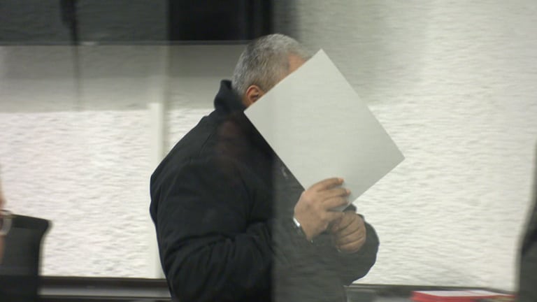 Der Angeklagte betritt mit  einer Mappe vor dem Gesicht den Gerichtssaal am Landgericht Stuttgart. Er soll im vergangenen Sommer einen Senior in Ludwigsburg mit einem Messer niedergestochen und getötet haben. (Foto: SWR)