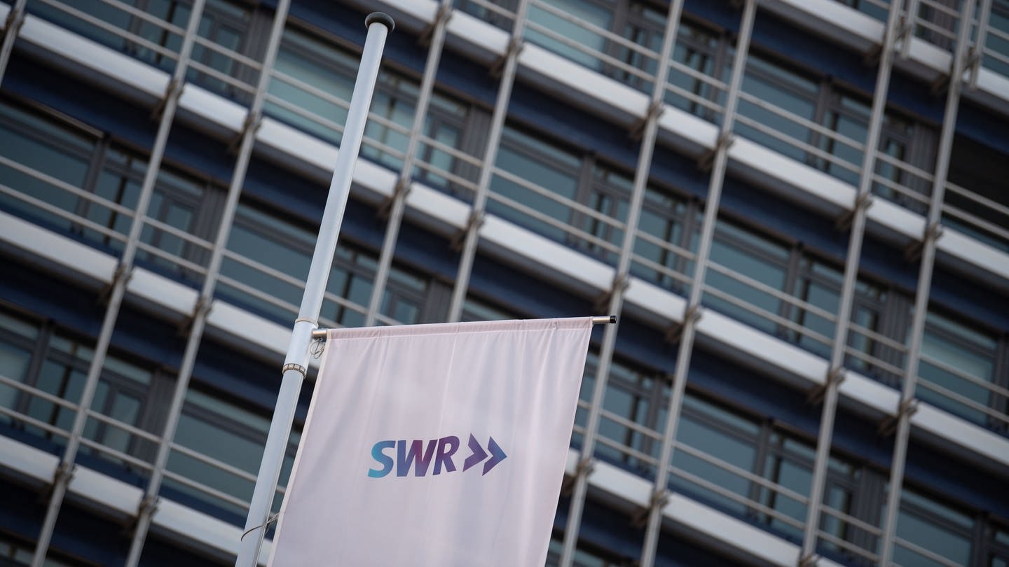 Wehende, weiße Flagge mit SWR-Aufdruck, im Hintergrund graue Fassade des Stuttgarter Funkhauses. (Foto: dpa Bildfunk, picture alliance/dpa | Marijan Murat)