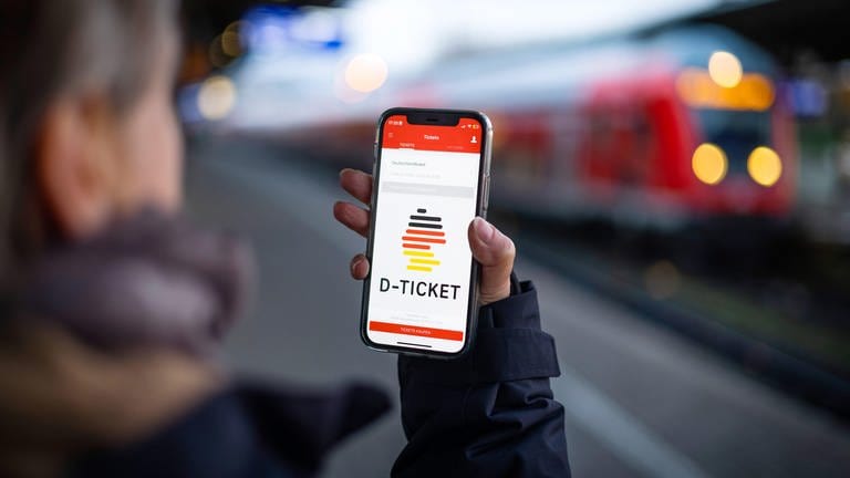 Eine Frau schaut am Bahnsteig auf das Deutschlandticket in ihrer Smartphone-App: Ab dem 1. Mai gilt im Nah- und Regionalverkehr das neue Angebot.