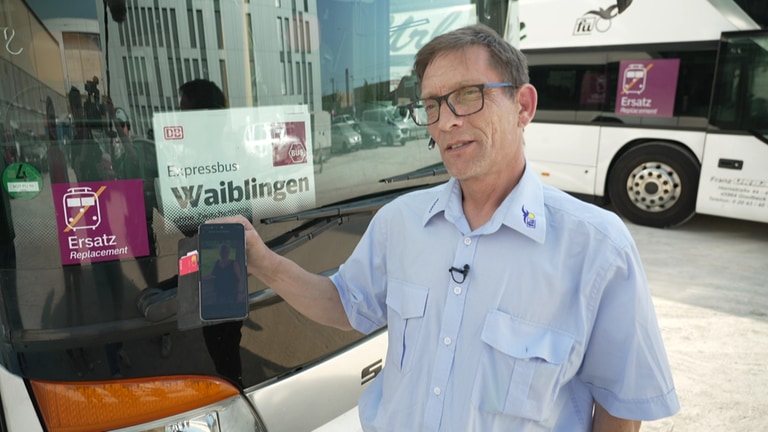 Busfahrer steht vor dem Expressbus nach Waiblingen und zeigt auf dem Handy ein Foto seiner Frau (Foto: SWR)