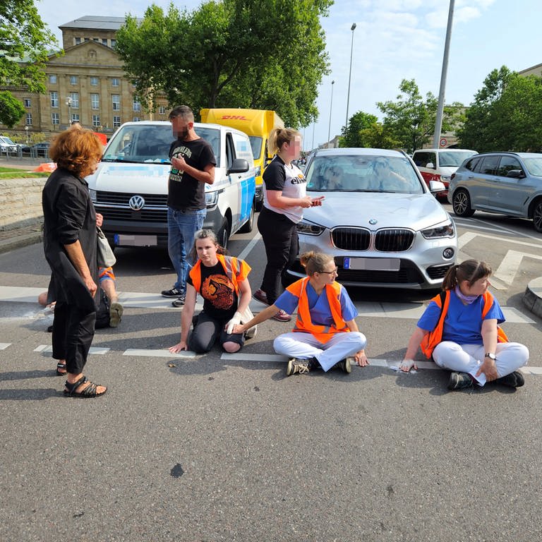 Klimaaktivsten sitzen auf der Straße, dahinter stehende Autos (Foto: SWR, Andreas Rosar, Fotoagentur Stuttgart )