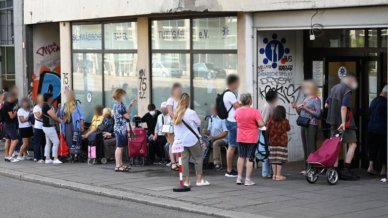 Menschen stehen in einer Schlange und warten vor einem Tafelladen. (Foto: dpa Bildfunk, picture alliance/dpa | Bernd Weißbrod)