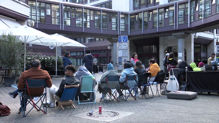 Menschen mit Stühlen und Kissen vor Bürgerbüro und Ausländerbehörde in Stuttgart.