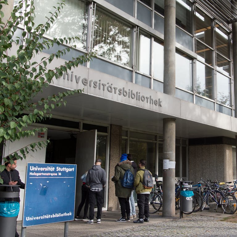 Studenten stehen vor der Universitätsbibliothek der Universität Stuttgart: Die UB ist infolge eines Schwelbrandes aktuell kaum nutzbar.
