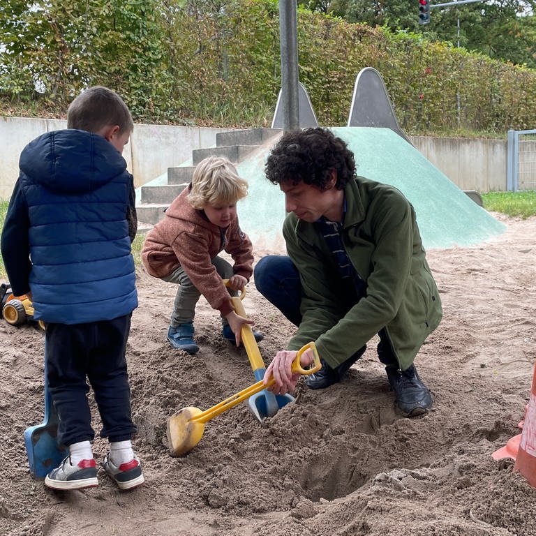 Florian Treßelt sitzt in einem Sandkasten mit Kindern. Der 35-Jährige lässt sich gerade zum Pädagogen umschulen. (Foto: SWR)