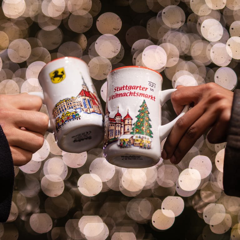 Zwei Menschen stoßen mit Glühwein auf dem Stuttgarter Weihnachtsmarkt 2022 an (Archivbild).