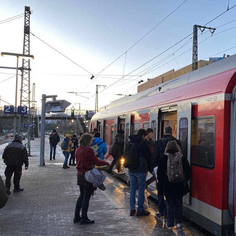 Eine S-Bahn hält und Fahrgäste steigen ein.