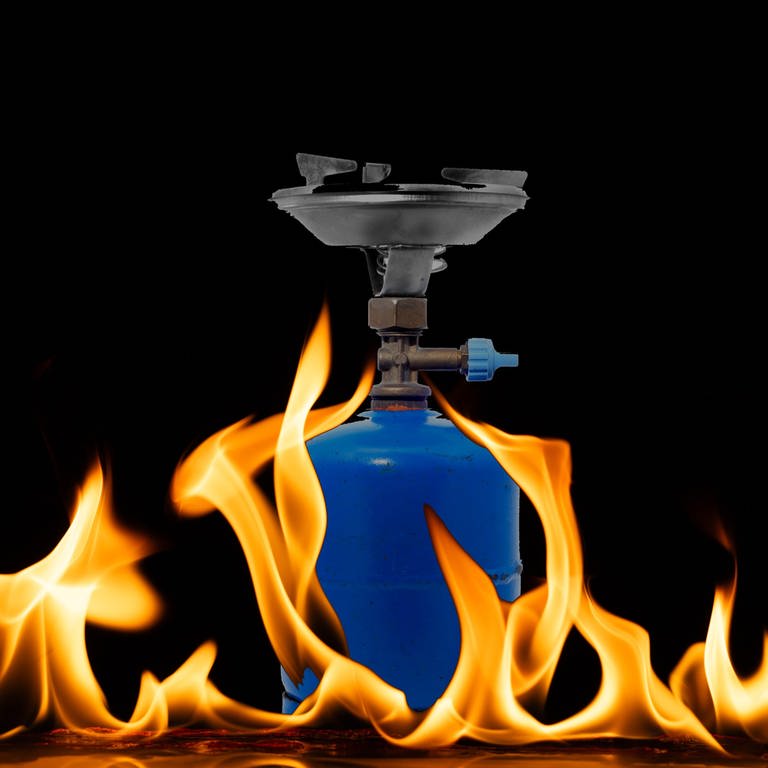 Ein Campingkocher mit Gaskartusche steht in züngelnden Flammen (Sympolbild). (Foto: IMAGO, IMAGO / Design Pics & Wavebreak Media Ltd | Montage: SWR)