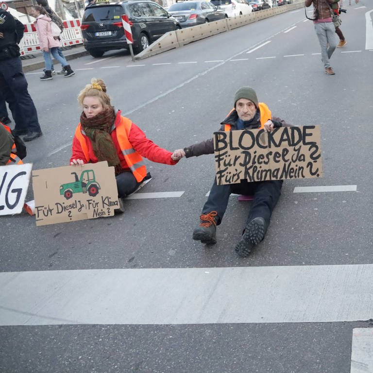 Klima-Protest: Aktivisten der Letzten Generation haben in Stuttgart eine Straße blockiert. Auf Schilder hatten sie Traktoren gemalt und geschrieben: "Blockade für Diesel Ja? Fürs Klima Nein?" (Foto: 7Aktuell)