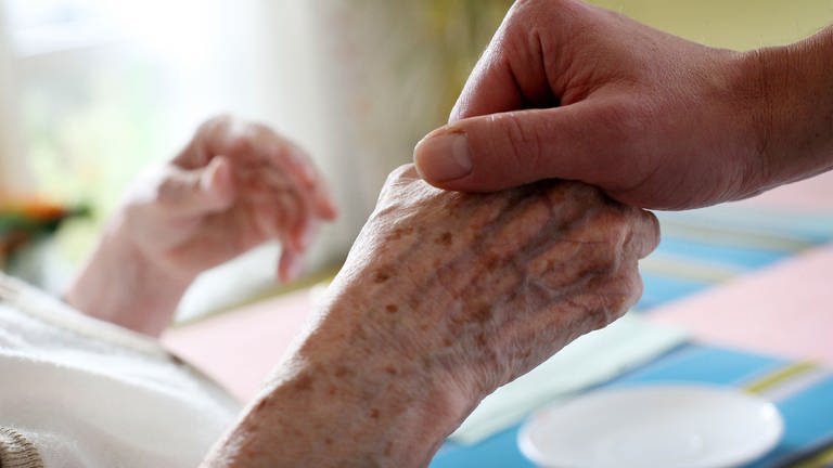 Ein Pfleger hält in einem Pflegeheim die Hand einer Bewohnerin. Bewohner und Mitarbeitende sollen in einem neuen Pflegeheim vor Diskriminierung geschützt werden.
