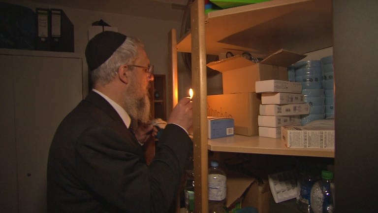 Rabbi spürt im Licht eines Streichholzes mit einer Vogelfeder Krümel auf. Das gehört zur rituellen Reinigung vor dem Pessach-Fest.