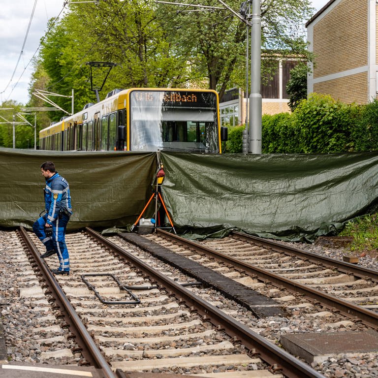 Eine Stadtbahn steht an einer Haltestelle in Stuttgart. Die tödliche Unfallstelle wurde von den Rettungskräften mit einer grünen Plane abgeschirmt. 