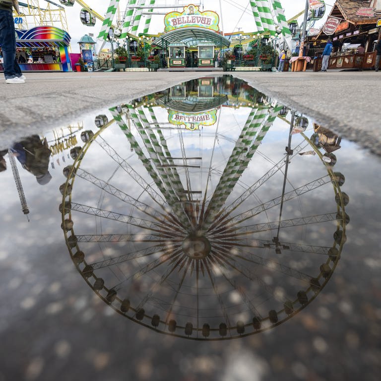 Ein Riesenrad spiegelt sich in einer Pfütze auf dem Festgelände des Stuttgarter Frühlingsfestes.  (Foto: dpa Bildfunk, picture alliance/dpa | Marijan Murat)