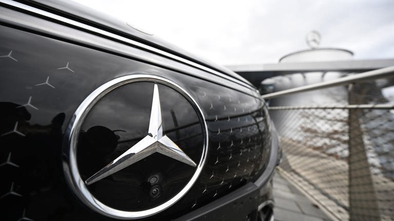 Vor einer Mercedes-Benz-Niederlassung steht ein Fahrzeug des Autobauers. Der Mercedes-Stern ist prominent im Vordergrund.