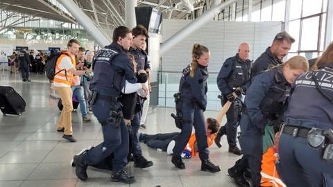 Einsatzkräfte der Polizei bringen Demo-Teilnehmer aus dem Terminal 3 des Flughafens Stuttgart.