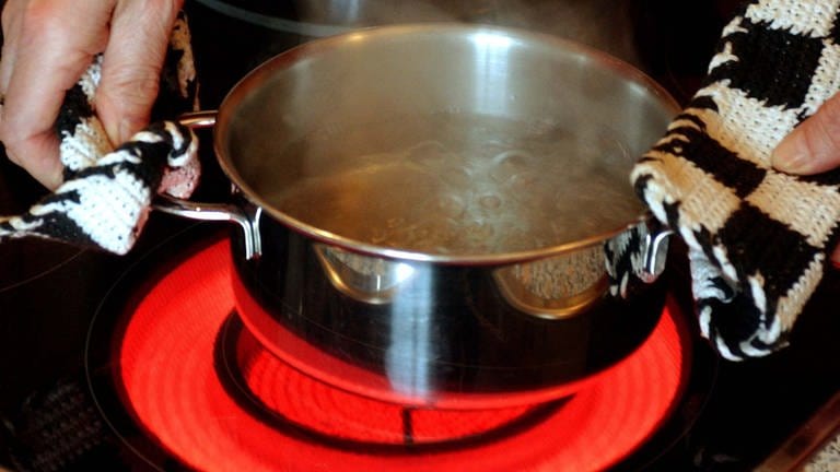In einem Kochtopf auf einem elektrischen Herd wird Wasser abgekocht.