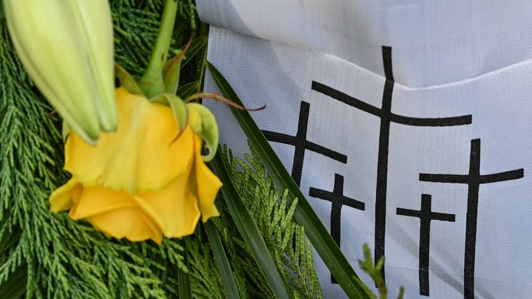 Eine gelbe Rose und schwarze Kreuze auf weißem Stoff: Symbolbild zum Volkstrauertag (Foto: dpa Bildfunk, Picture Alliance)